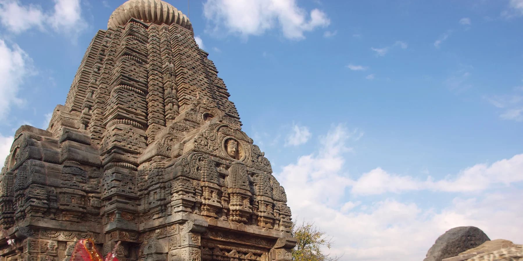 Carved stone tower of Basheshwar Mahadev Temple in Bajaura against the sky