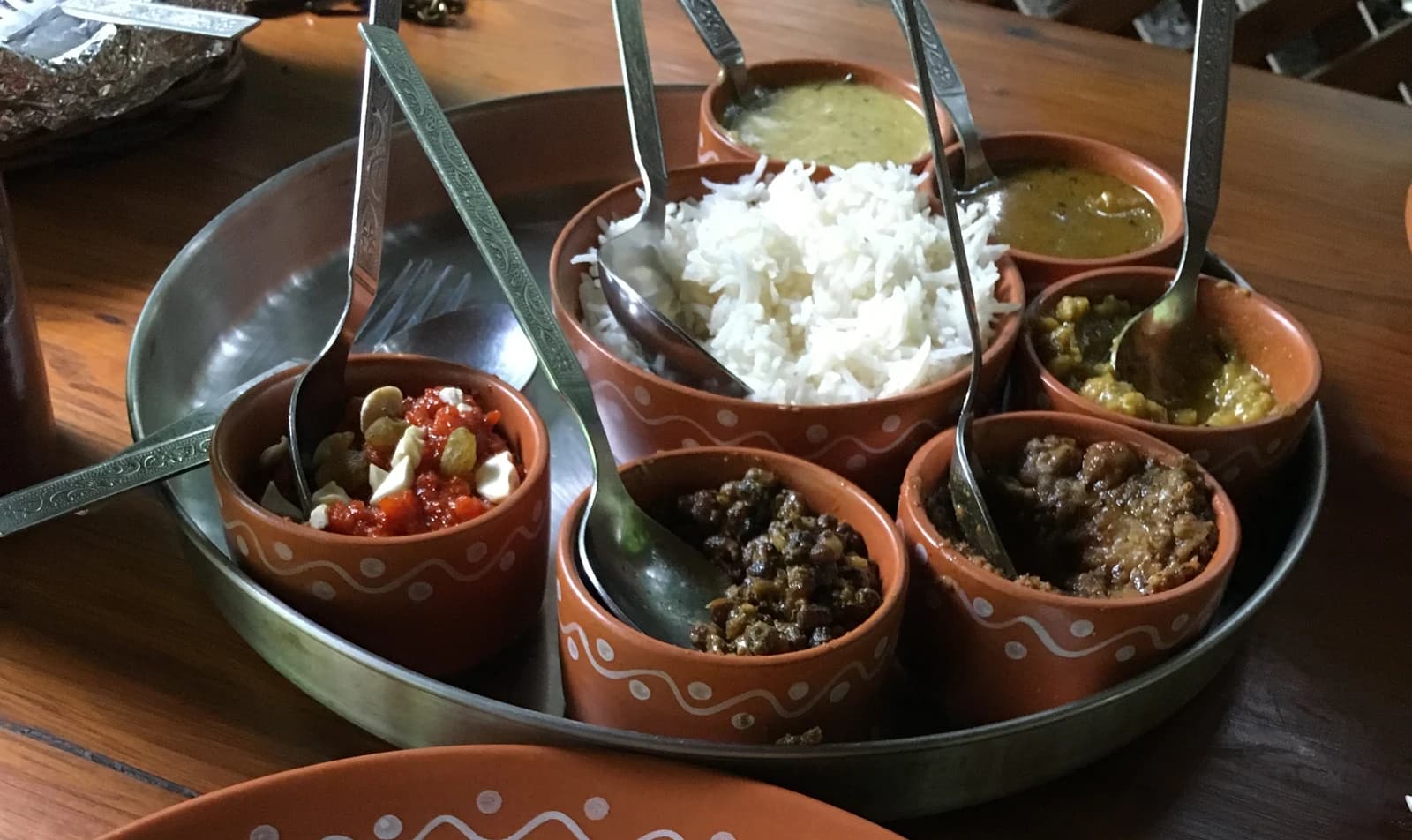 Rice and separate dishes in decorated terracotta bowls on a metal tray