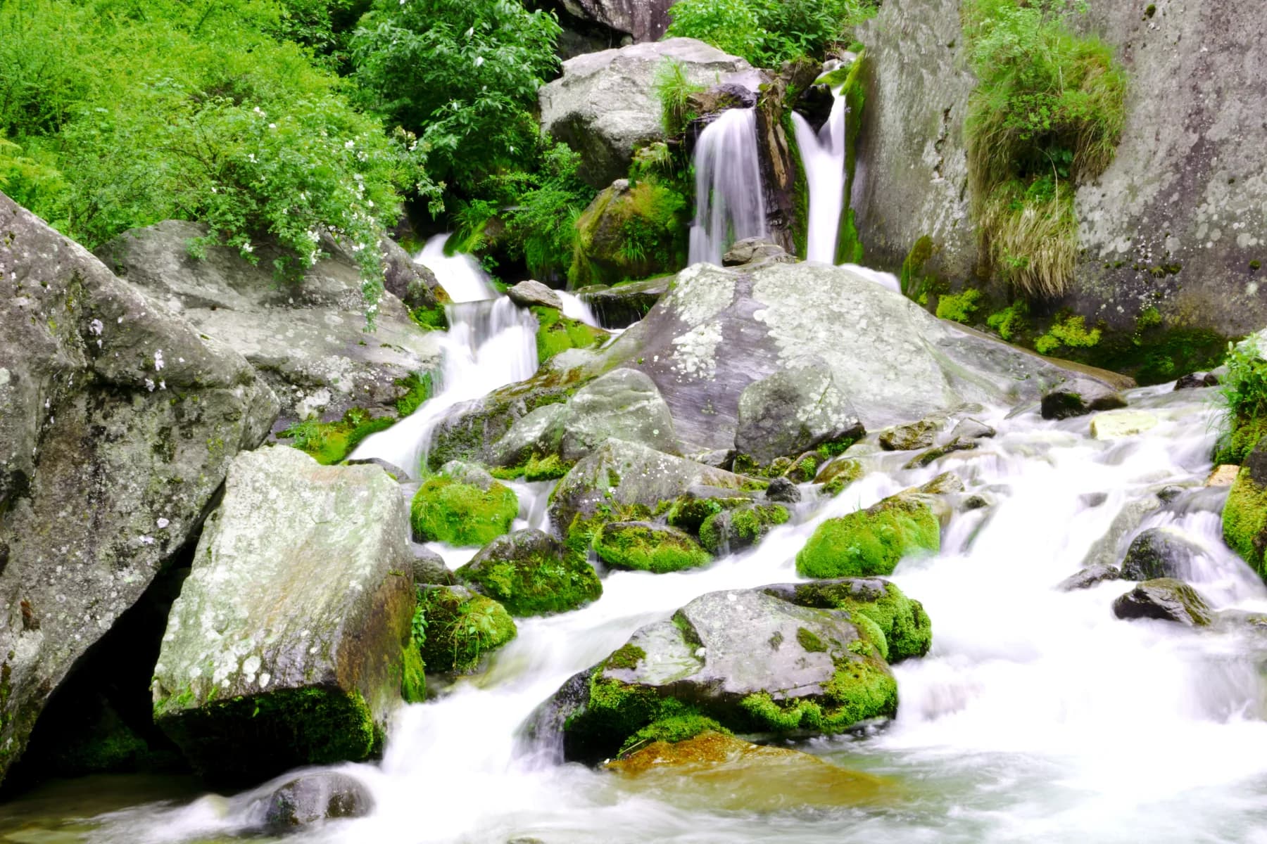Water flowing between moss-covered rocks at Jogini Falls near Manali