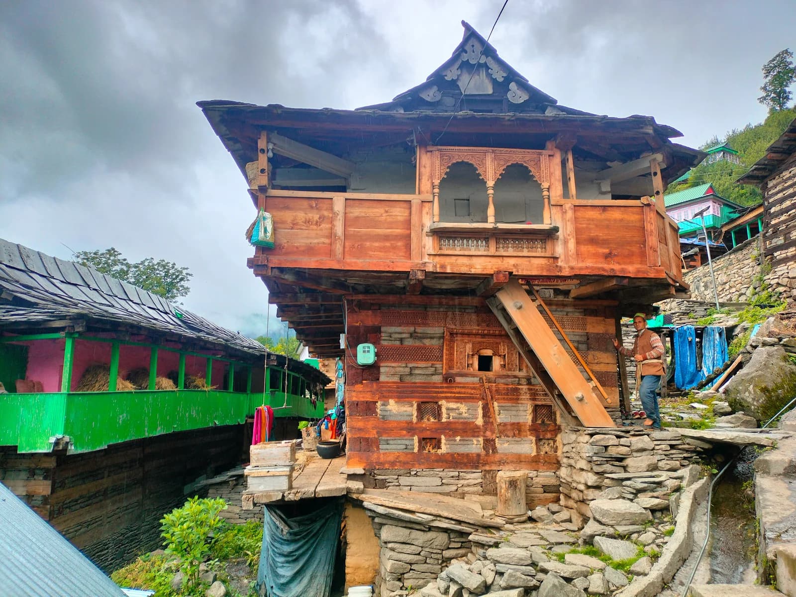 Stone-and-timber house in Tangnu with a carved wooden balcony and an exterior ladder