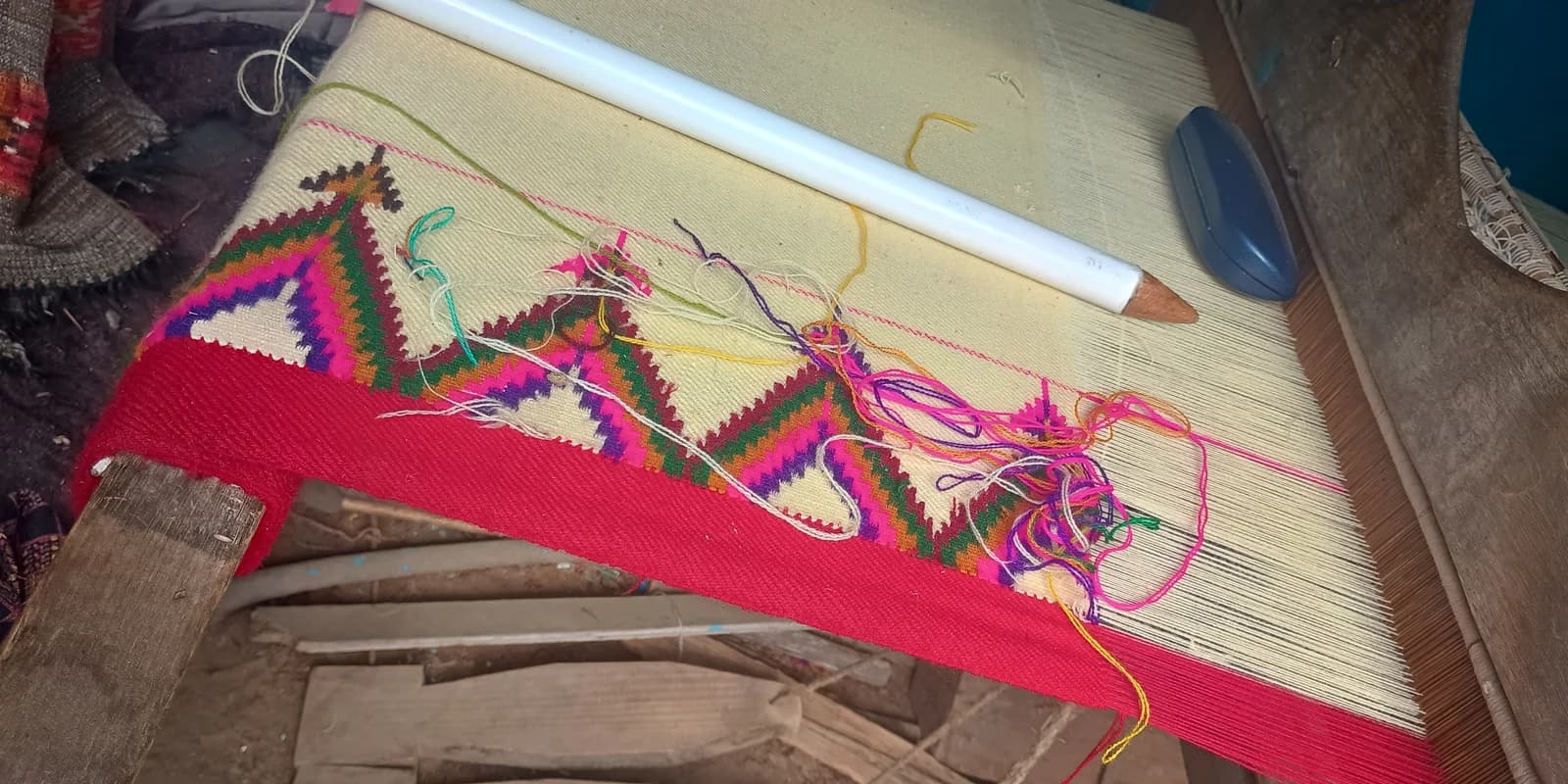 Multicoloured pattu border and loose yarn on a wooden handloom in Kullu district