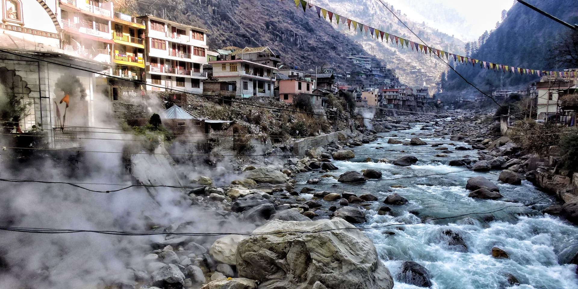 Steam rising beside the Parvati River at Manikaran, with the town on the hillside