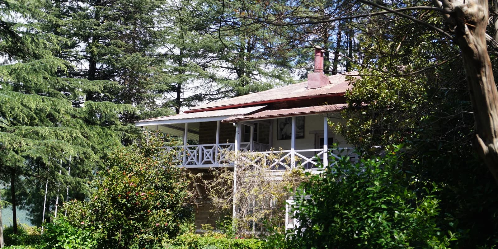 Roerich Memorial House with a red roof and white balcony among trees in Naggar