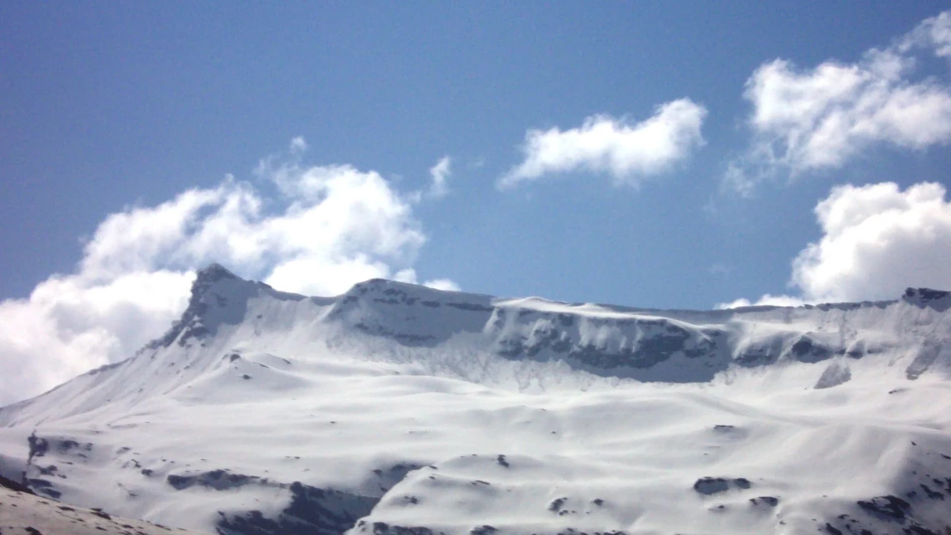Snow-covered Himalayan ridges seen from Rohtang Pass under a blue sky