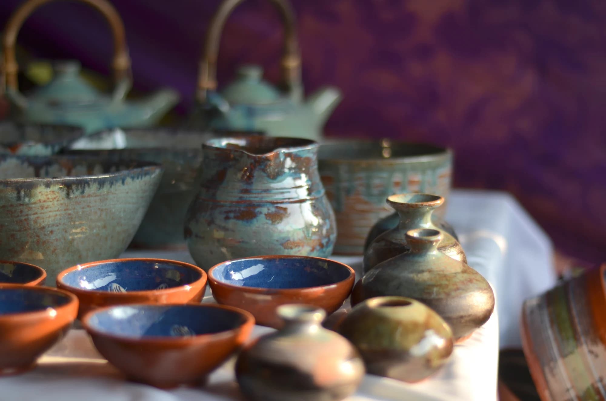 Blue-interior bowls and pale glazed jugs from Andretta pottery displayed at Dastkar Bazaar in Delhi