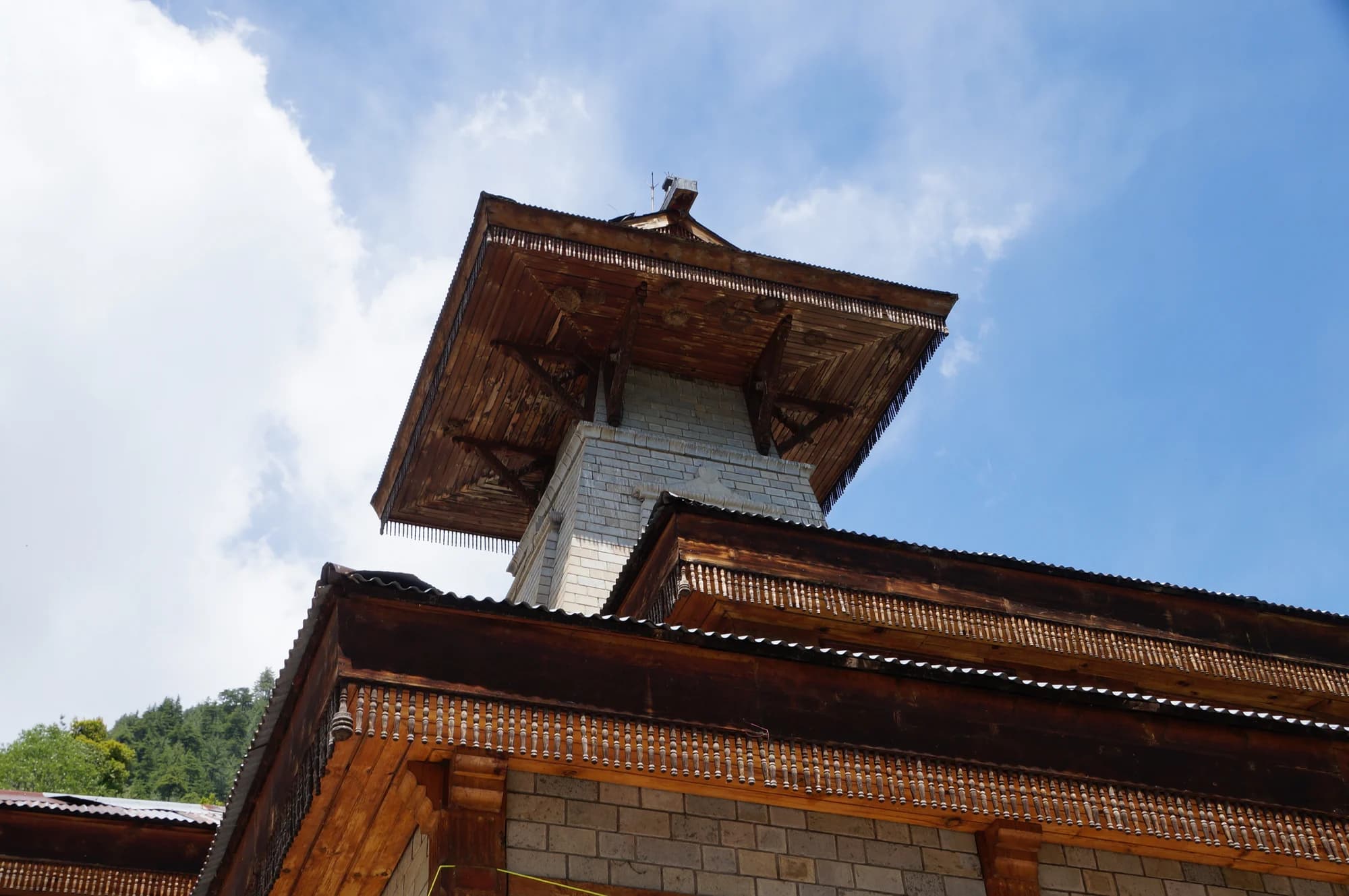 Projecting timber roofs and pale stone walls of Manu Rishi Temple in Old Manali